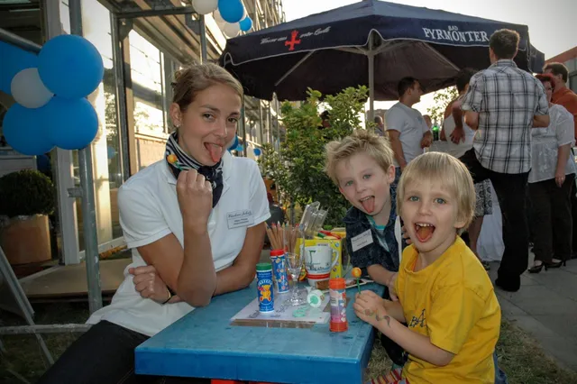 Mitarbeiterin und zwei Kinder am Basteltisch beim Kinderprogramm des Eröffnungsfests