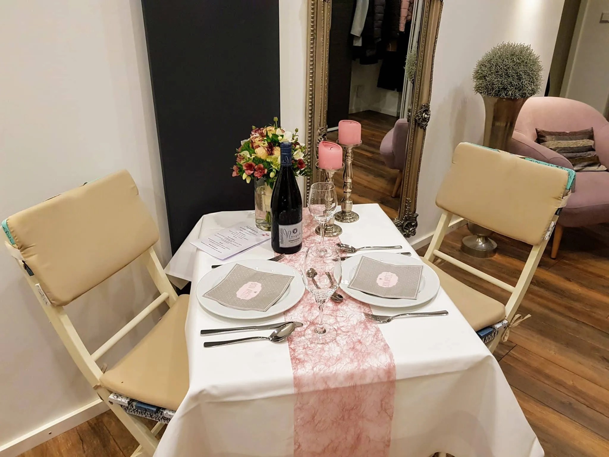 Festlich gedeckter Restauranttisch mit weißer Tischdecke und rosa Läufer