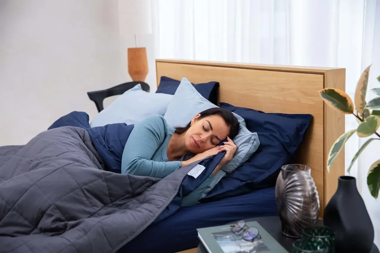 Frau schläft entspannt unter einer grauen Gewichtsdecke im Bett